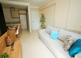 Spacious modern living room with a white couch, blue pillows, and a compact dining area.