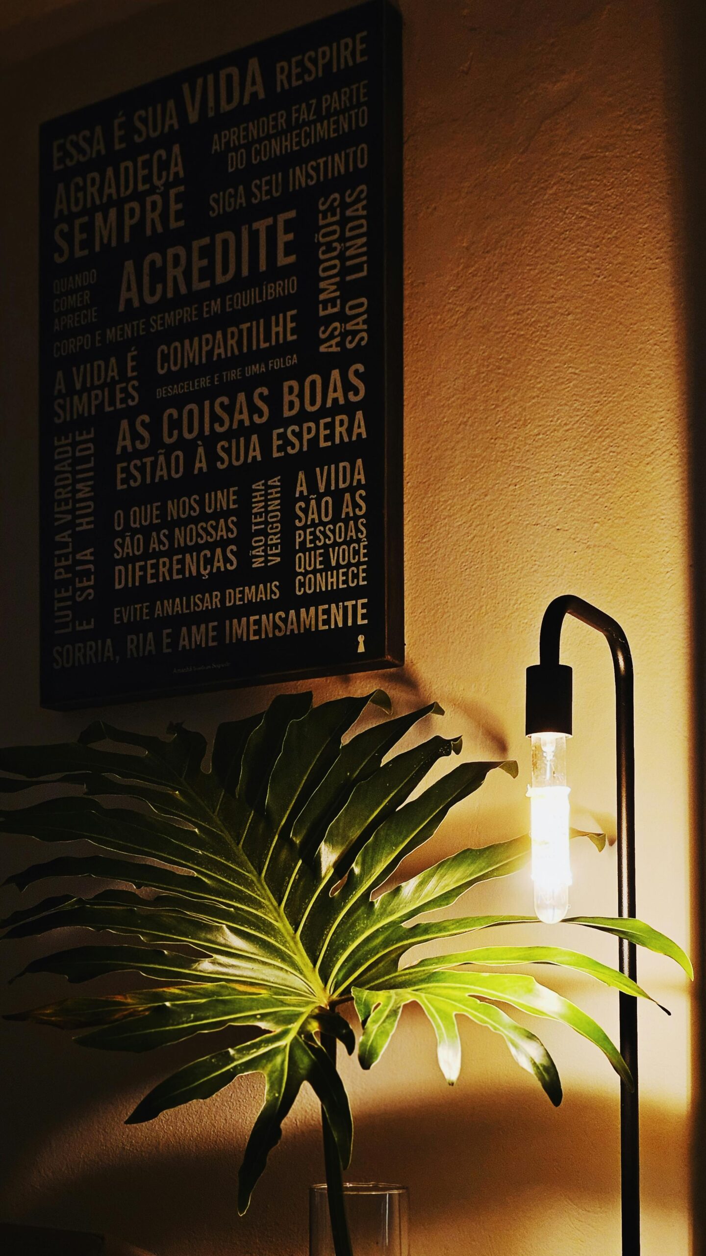 Cozy room with lamp, tropical plant, and motivational text on wall.